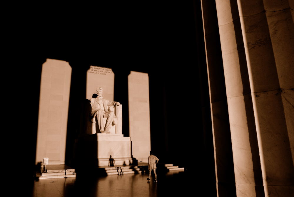 A jogger takes a break and walks up to the statue of Abraham Lincoln inside the Lincoln Memorial. Dawn, Washington DC.