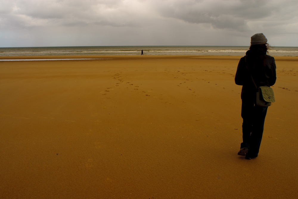 A woman standing on Omaha Beach. An overcast day in Normandy, France.