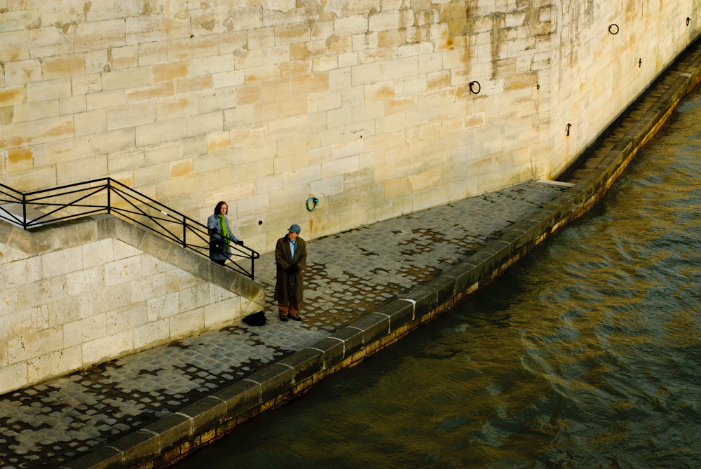 Man and woman walking along the River Seine in Paris.